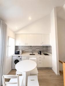 a white kitchen with a white table and chairs at Casa do Leme in Nazaré