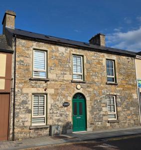 an old stone building with a green door at Coach House Accommodation - Room 9 in Carrick on Shannon