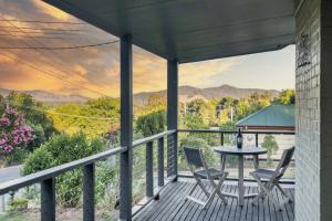 a porch with two chairs and a table with a view at Hillhouse in Myrtleford
