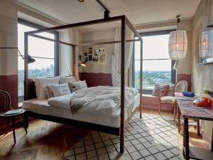 a bedroom with a canopy bed in front of a window at 25hours Hotel Das Tour in Düsseldorf +51 photos