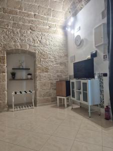 a living room with a brick wall and a tv at San Domenico 9 in Bitetto