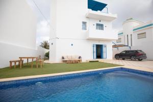 a villa with a swimming pool in front of a house at Villa Aura in Ouled Yaneg