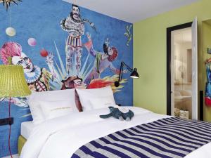 a bedroom with a large bed with a painting on the wall at 25hours Hotel beim MuseumsQuartier in Vienna