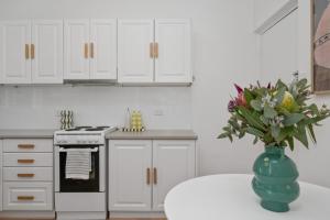 a kitchen with white cabinets and a vase of flowers on a table at Oak and Olive - Glenelg in Glenelg