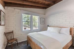 a bedroom with a bed and a chair and a window at Gangurru in Myrtleford