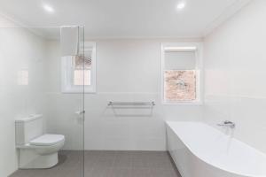 a white bathroom with a toilet and a shower at Gangurru in Myrtleford +31 photos