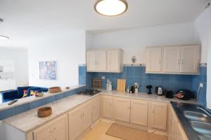 a large kitchen with white cabinets and blue tiles at Villa Aura in Ouled Yaneg