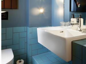 a bathroom with a white sink and blue tiles at 25hours Hotel The Goldman in Frankfurt