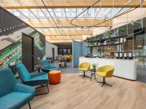 a lobby with chairs and tables and a counter at ibis Styles Delft City Centre in Delft