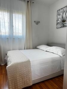 a bedroom with a white bed and a window at Sunset Hill Apartments in Brodarica