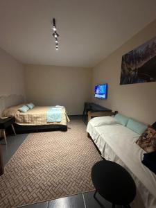 a bedroom with two beds and a tv on the wall at Pousada Central Araquari in Araquari