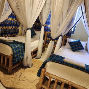 a bedroom with two beds and a window with curtains at M- NET LUXURIOUS HOTEL KAGADi in Kagadi