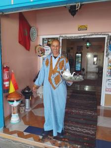 a man holding a plate of food in a room at Gîte d'étape Imane Café ET Restaurant in Aït Amar
