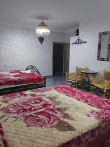 a bedroom with two beds with red sheets and a table at Gîte d'étape Imane Café ET Restaurant in Aït Amar