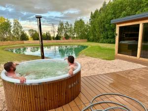 two men in a jacuzzi tub next to a pool at Sodyba Anykščių raj. in Anykščiai