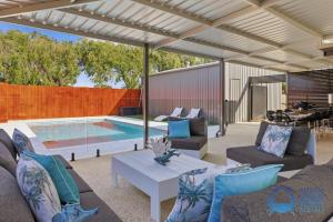 a patio with a table and chairs and a pool at Mandurah Poolside Retreat in Coodanup