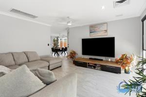 a living room with a couch and a flat screen tv at Mandurah Poolside Retreat in Coodanup