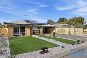 a house with a green lawn in front of it at Mandurah Poolside Retreat in Coodanup