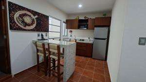a kitchen with a counter with chairs and a refrigerator at Bungalows Huerta del Mar in San Blas