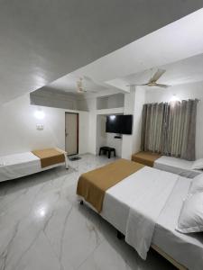 a bedroom with two beds and a flat screen tv at Hotel Prime Lodging in Aurangabad