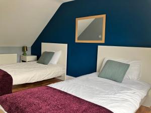 two beds in a room with a blue wall at Silver Birch House in Laune Bridge