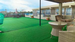 a balcony with a green floor with a table and chairs at Savannah suites Bel-Air in Gilgil