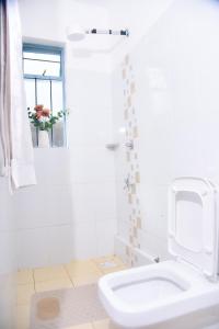 a white bathroom with a toilet and a sink at Savannah suites Bel-Air in Gilgil +9 photos