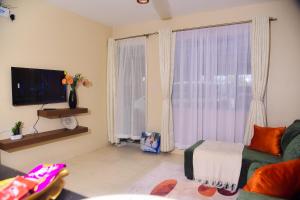 a living room with a couch and a large window at Savannah suites Bel-Air in Gilgil