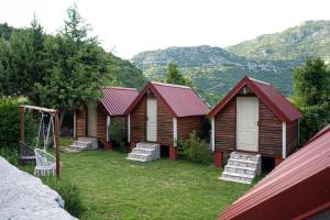 a group of wooden cabins with a swing at Vikendica,Bungalovi Lipska pećina in Cetinje