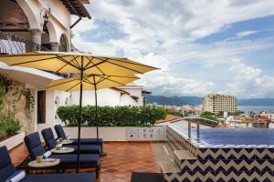 eine Terrasse mit Stühlen und einem Sonnenschirm auf einem Balkon in der Unterkunft BellView Hotel Boutique in Puerto Vallarta