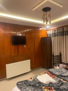 a room with two beds and a tv on a wall at Mussiaree Hotel in Murree