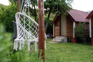 a white chair hanging from a pole in a yard at Vikendica,Bungalovi Lipska pećina in Cetinje +67 photos