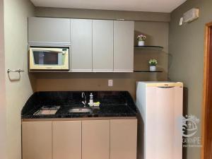 a kitchen with a sink and a microwave and a refrigerator at Flat no Condomínio Metrópolis - Ilha do Leite in Recife