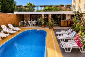 a swimming pool with white chairs and a table at Family Hotel Kosko in Chernomorets