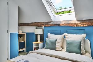 a bedroom with a bed with blue walls and a skylight at Appartement Houdan centre-ville in Houdan