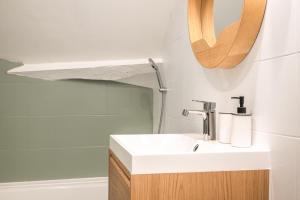 a bathroom with a sink and a mirror and a tub at Appartement Houdan centre-ville in Houdan