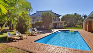 a swimming pool in front of a house at Caribbean Estates by MyResorts in Port Edward