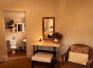 a bathroom with a table with a mirror and a chair at The Thatched Hideaway on Stanmore farm in Nottingham Road