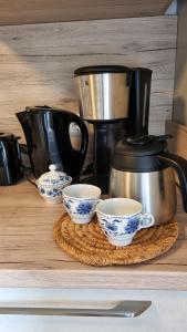 a coffee pot and three cups on a table at Ferienwohnung Hebestreit in Kirchworbis