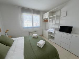 a white bedroom with a bed and a television at Ático en Cubelles playa in Cubelles +19 photos