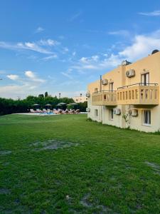 a building with a green field in front of it at Angelos Studios in Kos