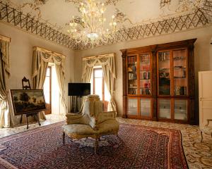 a living room with a chair and a chandelier at Villa del Gattopardo in Palermo +110 photos