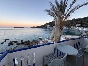 a balcony with a table and chairs and the ocean at Nikolas Rooms in Loutro +53 photos