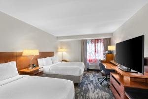 a hotel room with two beds and a flat screen tv at Fairfield Inn Boston Woburn in Woburn