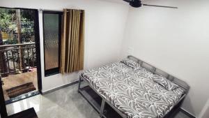 a bed sitting on a balcony next to a window at Hindlekar home stay in Malvan