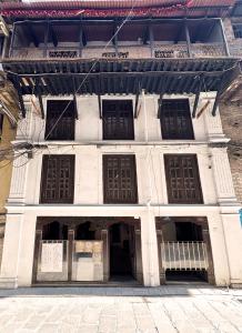 an old white building with brown doors and windows at Newa Inn Homestay in Kathmandu