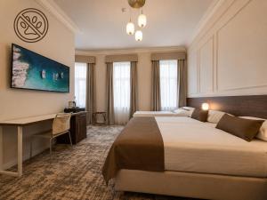 a hotel room with two beds and a desk at Hotel Villa Eugenia in Lovran