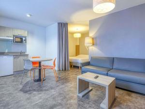 a living room with a couch and a table at Aparthotel Adagio Access Saint Nazaire in Saint-Nazaire