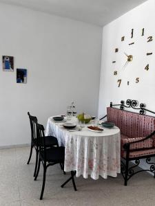 a dining room with a table with chairs and a clock at Appartement spacieux - Dar Chaabane plage in Nabeul