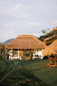 a house with a thatched roof with a grass at Muara Surf House - Yoyos beachfront in Sekongkang